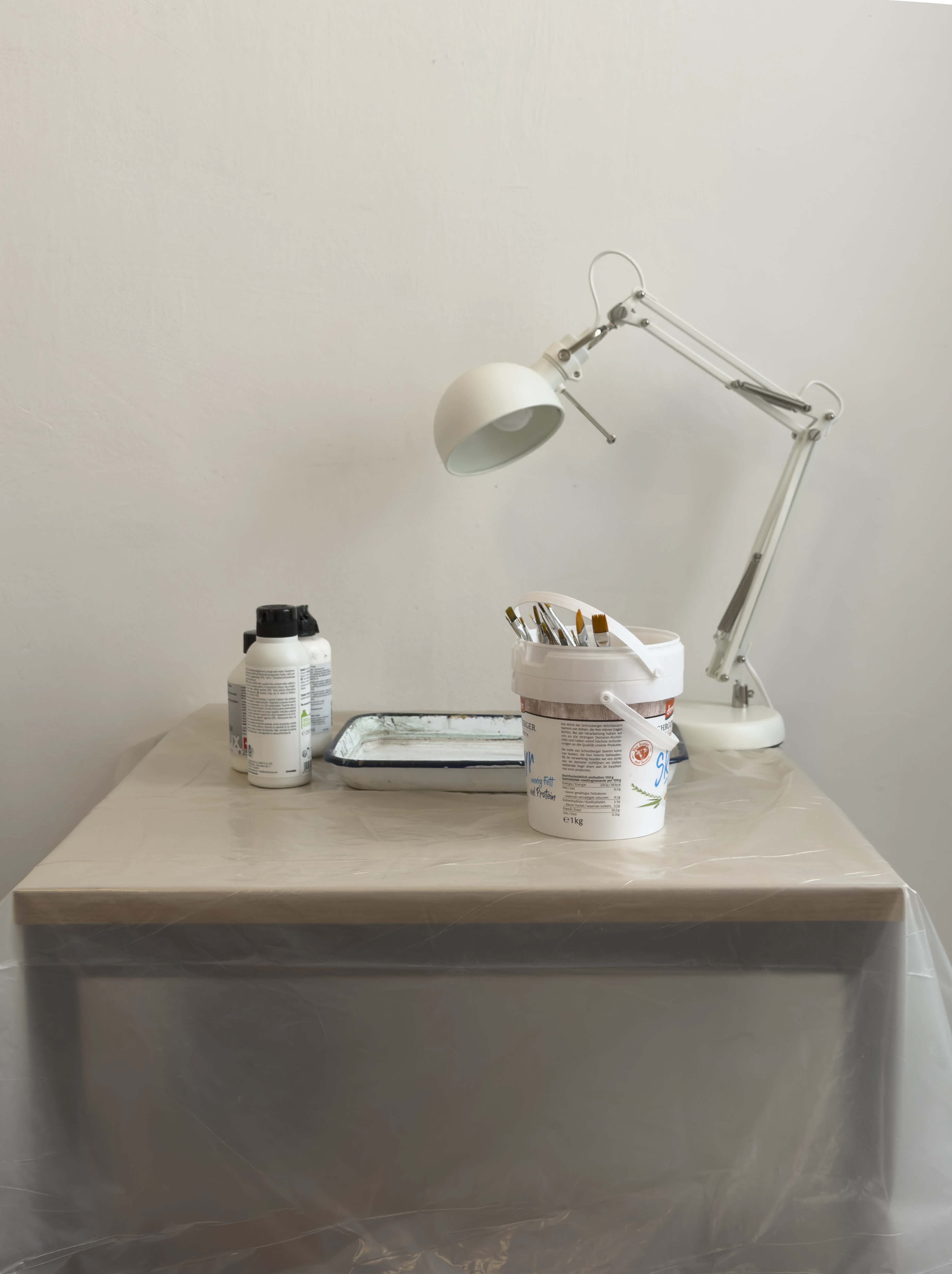 Exhibition announcement for John Miller’s I Am an Artist, featuring painting materials arranged on a plastic-covered table in Magaluf. 24 July 2026.